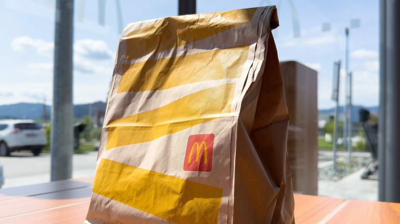 A bag of McDonald's sits on a table with a window in the background