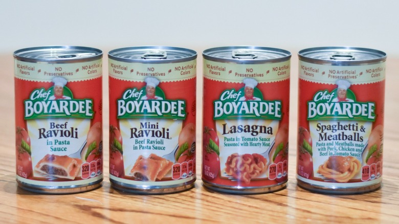 Four cans of Chef Boyardee pasta on a wooden table