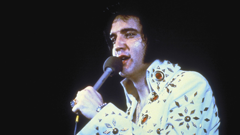 Elvis in white suit holding microphone