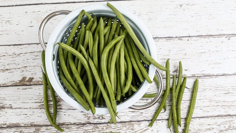 French green beens in a colander on a wooden table
