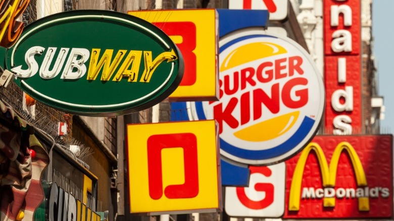 A close grouping of fast food restaurant signs along a street