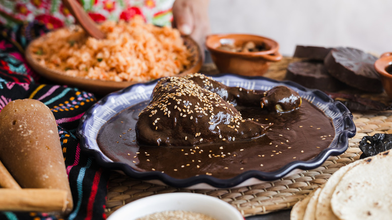 chicken mole sitting in a bowl on a table surrounding by other traditional Mexican food