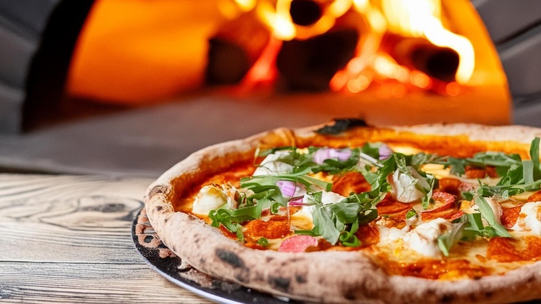 Hot pizza sitting in front of a wood-fired pizza oven