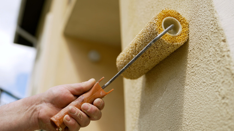 Person painting house exterior roller