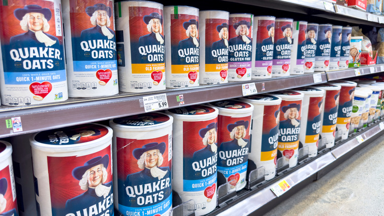 Two shelves at a grocery store full of Quaker Oats canisters