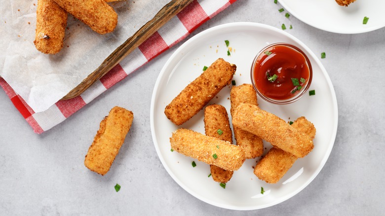 Mozzarella sticks on a white plate with sauce
