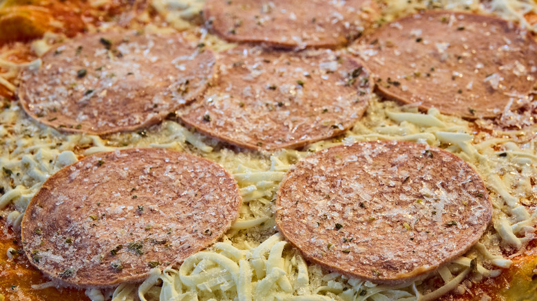 A close-up of a frozen pepperoni pizza, uncooked