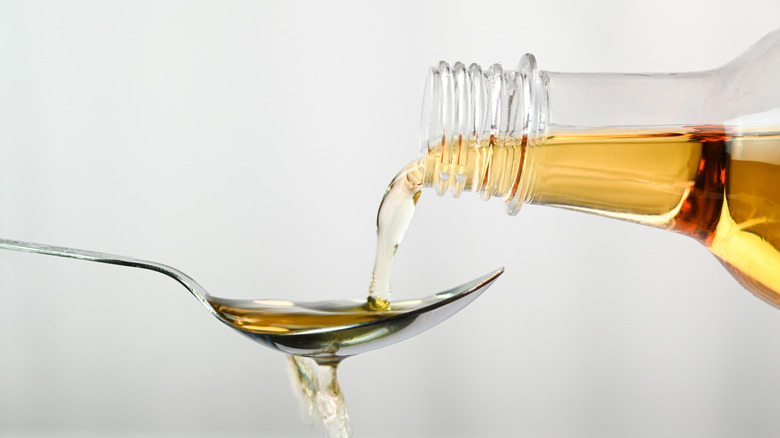pouring apple cider vinegar into a spoon