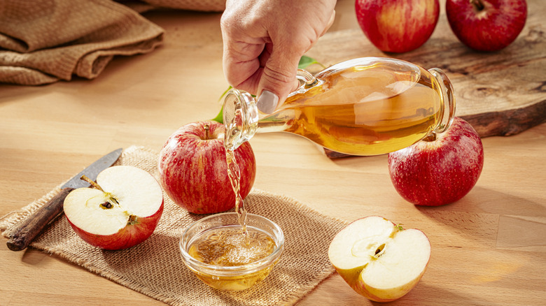 Person pouring apple cider vinegar into a small bowl