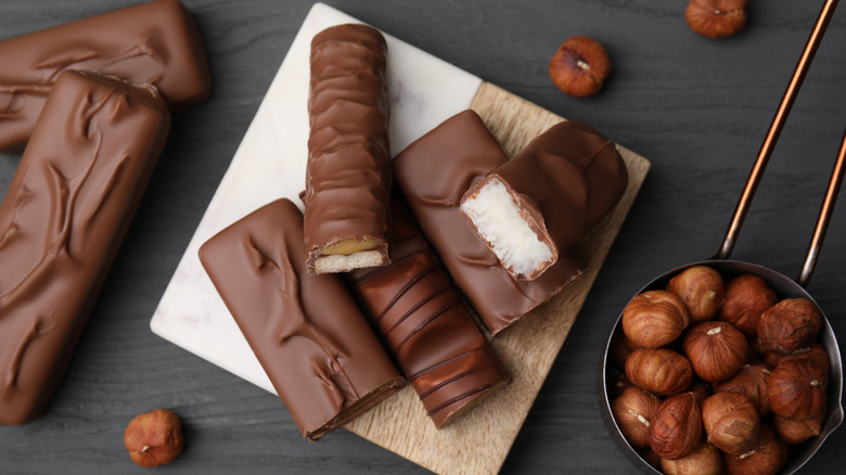 assorted unwrapped candy bars on a table with hazelnuts