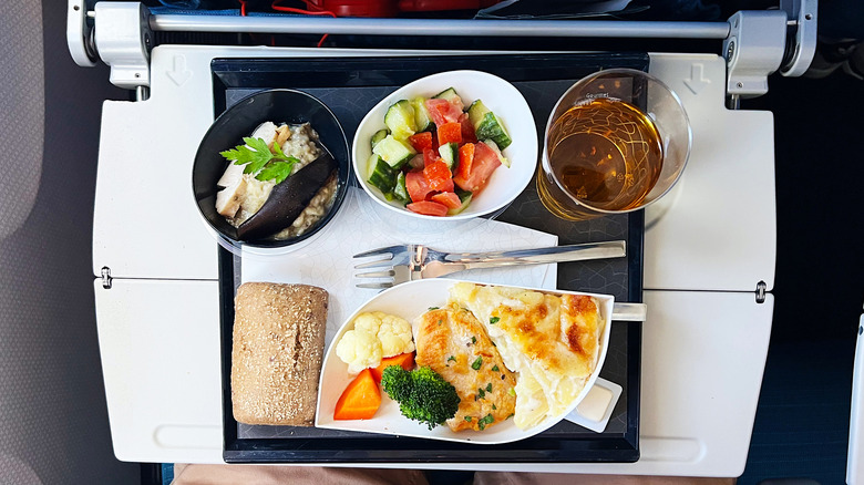 Chicken, mashed potatoes, salad, juice, and rice on an airplane tray table